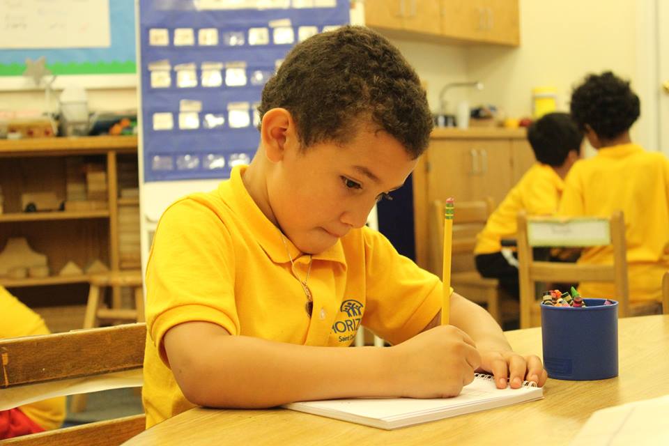 Young boy writing on a piece of paper with a pencil