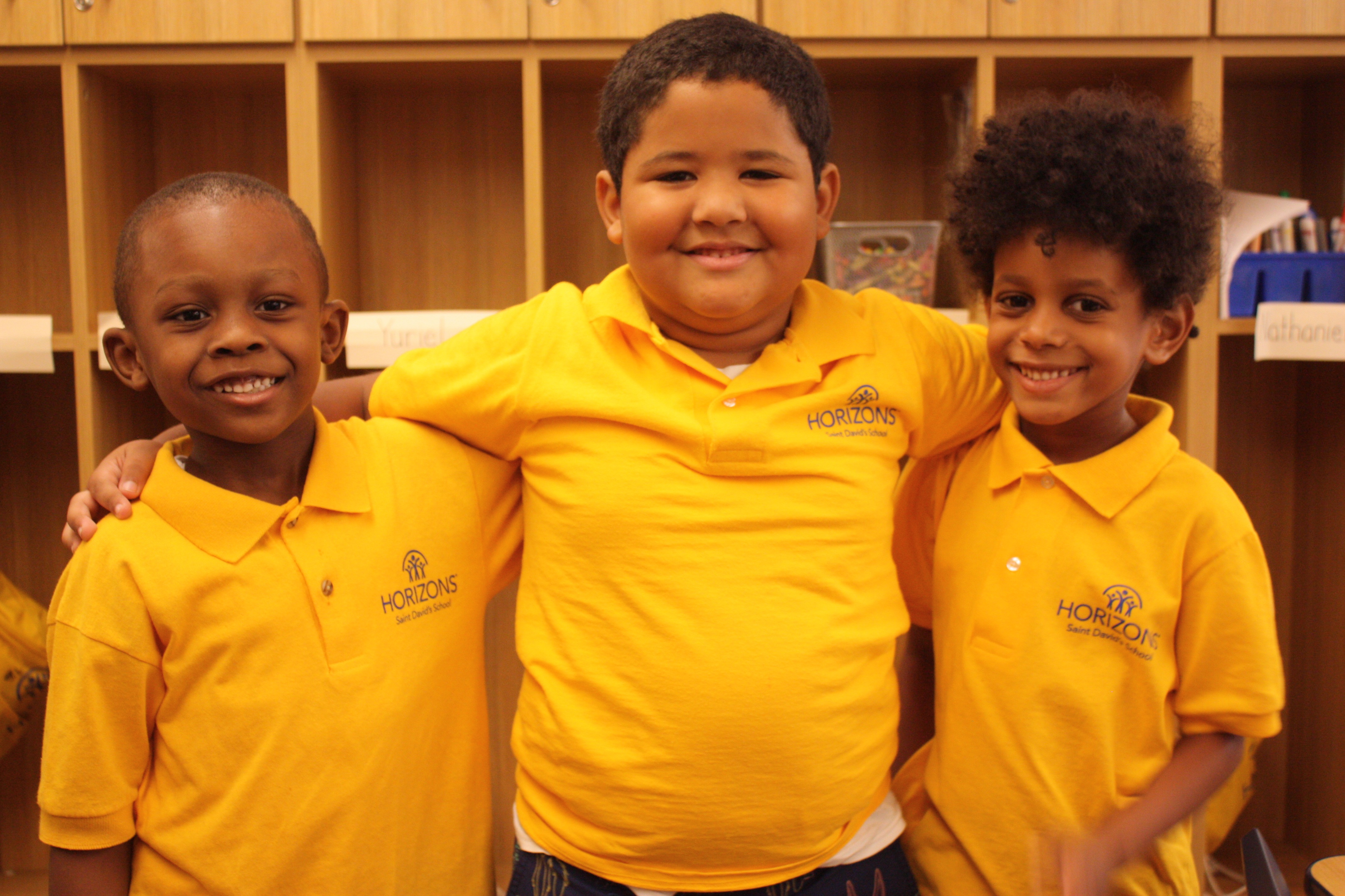 Three smiling young boys wearing yellow Horizons program shirts